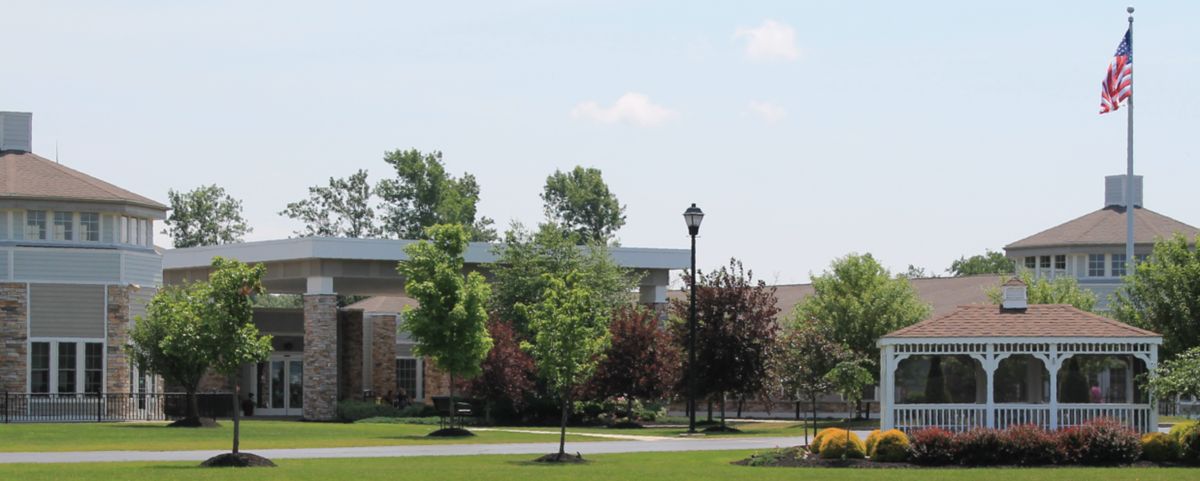 A scenic view of a landscaped area with trees, a building, and a pathway under a clear sky.