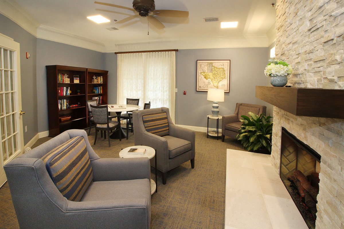 A cozy living room with comfortable seating, a fireplace, and a bookshelf.