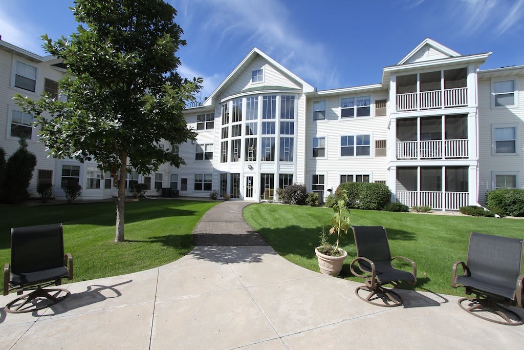 A sunny day view of a multi-story residential building with well-maintained landscaping.
