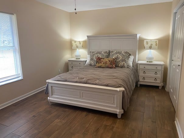 A cozy bedroom with a wooden bed, nightstands, and lamps providing a warm ambiance.