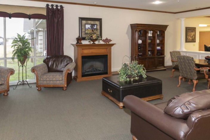 A cozy living room interior with a fireplace, armchairs, couch, and decorative elements.