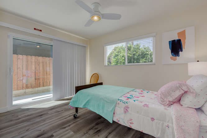 A minimalist bedroom with a single bed, large window, and sliding glass door.