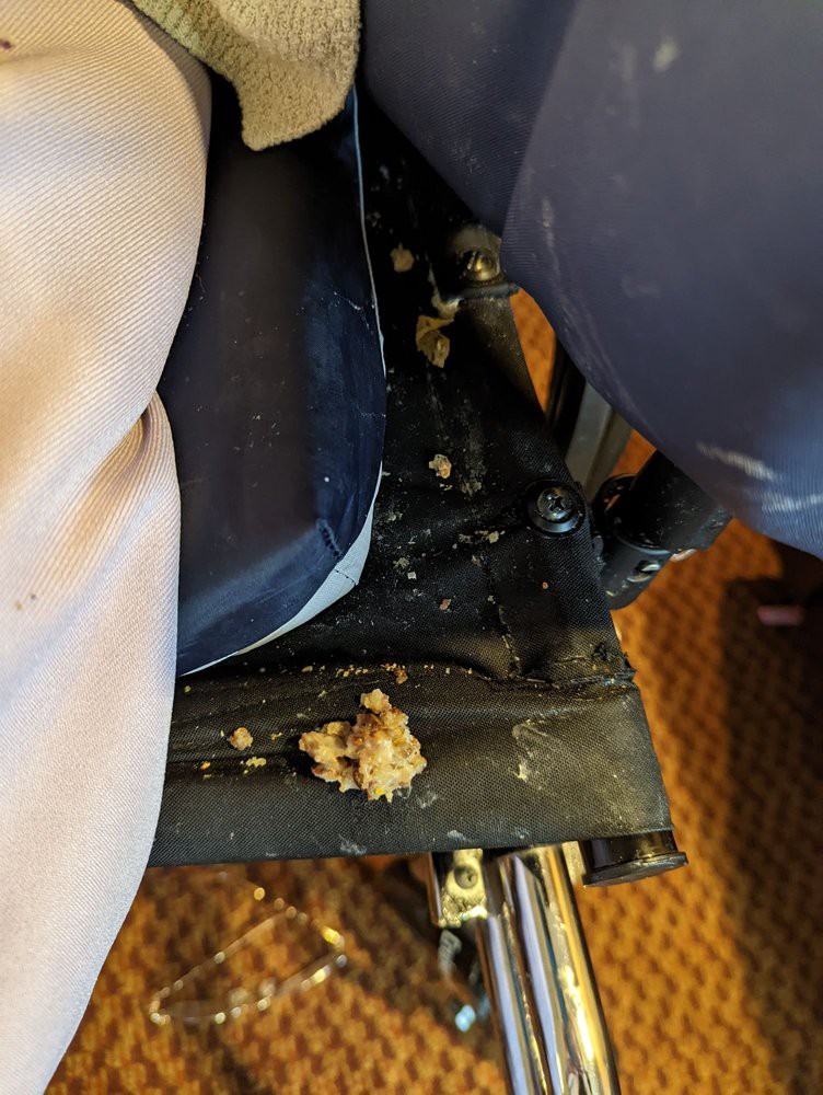 A messy airplane seat with food spill.