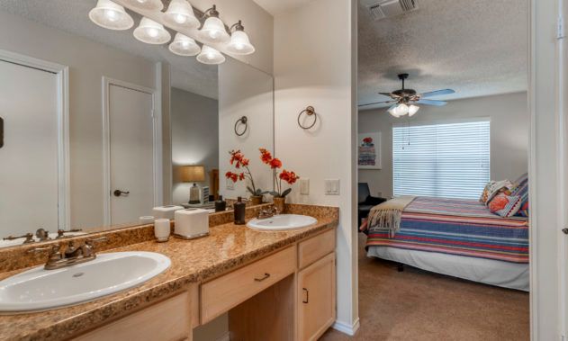 A cozy home interior featuring a bathroom with double sinks and an adjoining bedroom.
