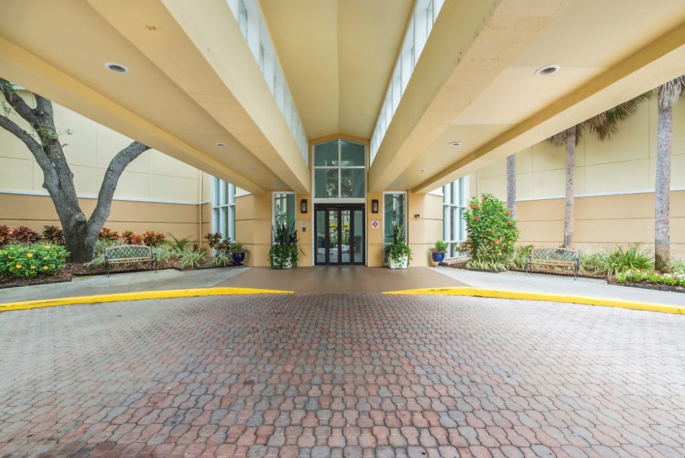 The image shows the entrance of a hotel featuring modern architecture and landscaping.