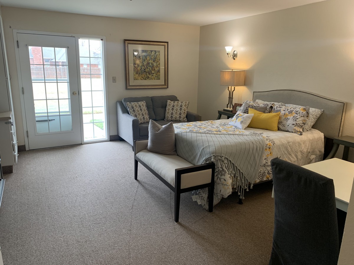 A cozy bedroom with modern decor, featuring a bed, sofa, and ample natural light.