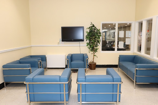 A modern waiting area featuring comfortable blue seating and a television.