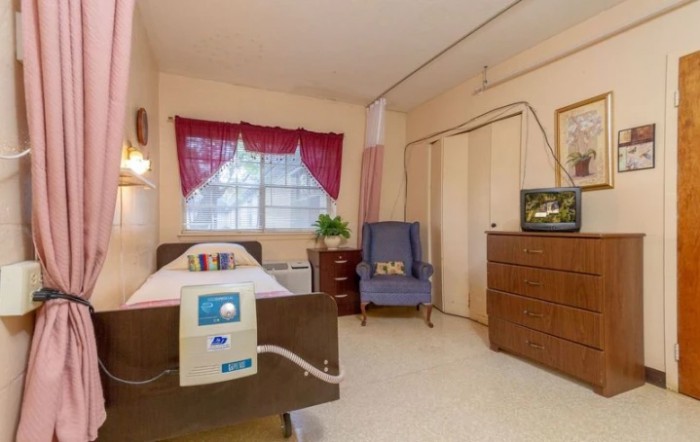 A cozy hospital room with a bed, comfortable chair, and television.