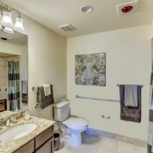 A clean and modern bathroom with a sink, toilet, mirror, and decorative wall art.