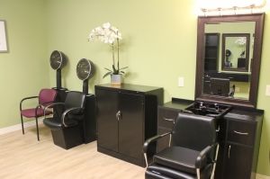 A hair salon interior featuring styling chairs, a mirror, and a pair of hair dryers.