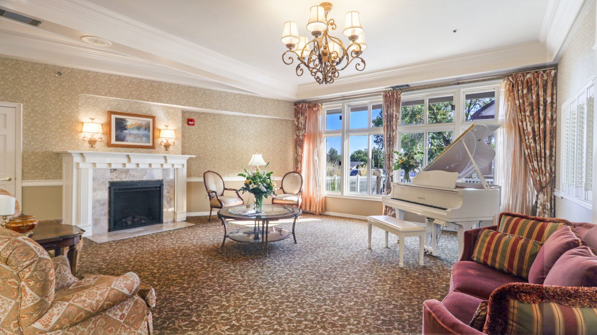 Elegant living room with a grand piano and a chandelier.