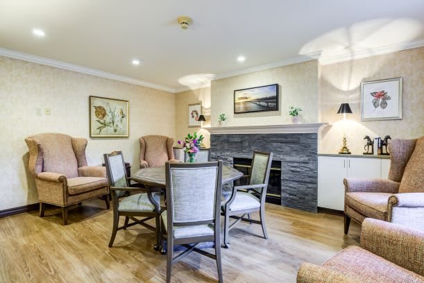 A cozy living room featuring a dining table with chairs, armchairs, a fireplace, and elegant decor.