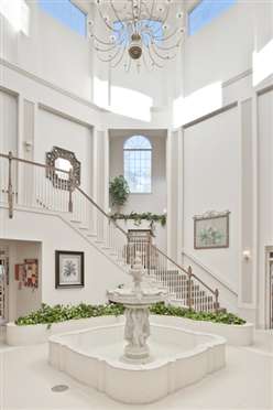 A grand foyer with a sweeping staircase, abundant natural light, and elegant decor.
