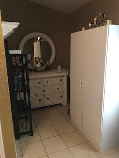 A cozy room setup featuring a white dresser with a round mirror, alongside a wardrobe and a black shelf.