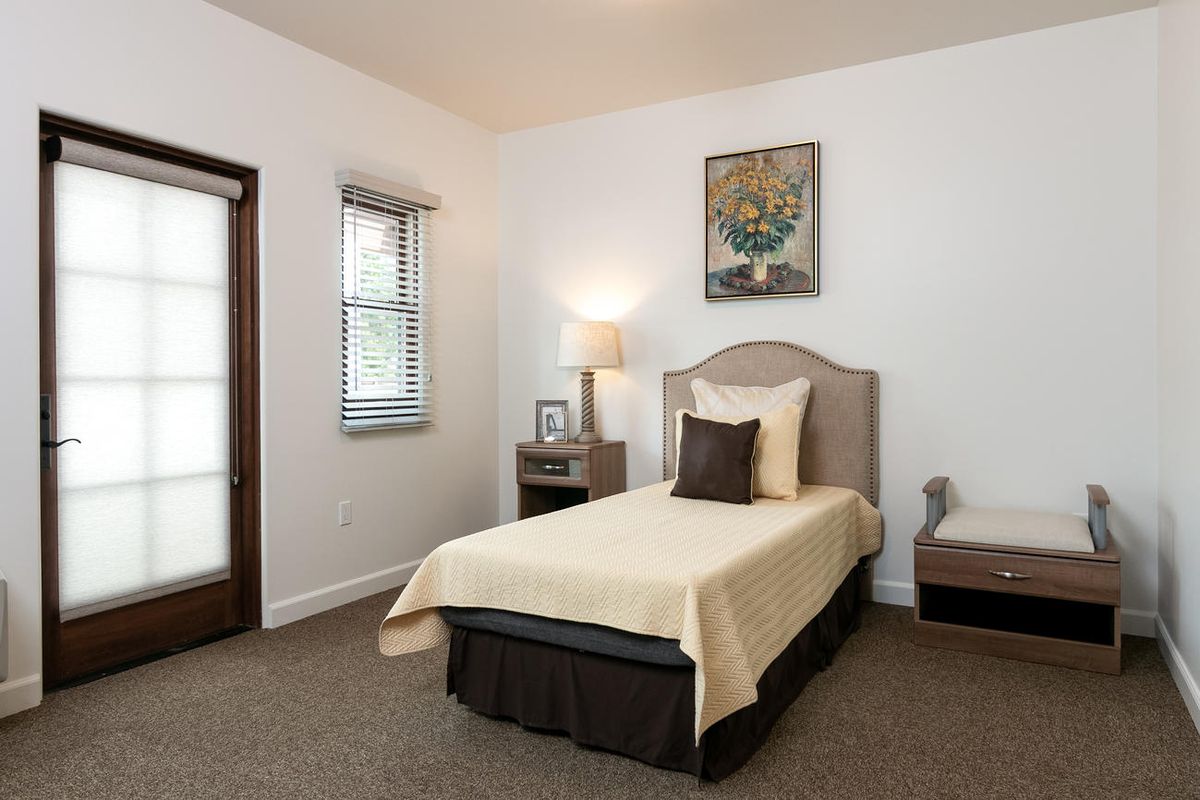 A cozy bedroom with a single bed, nightstand, and framed artwork.