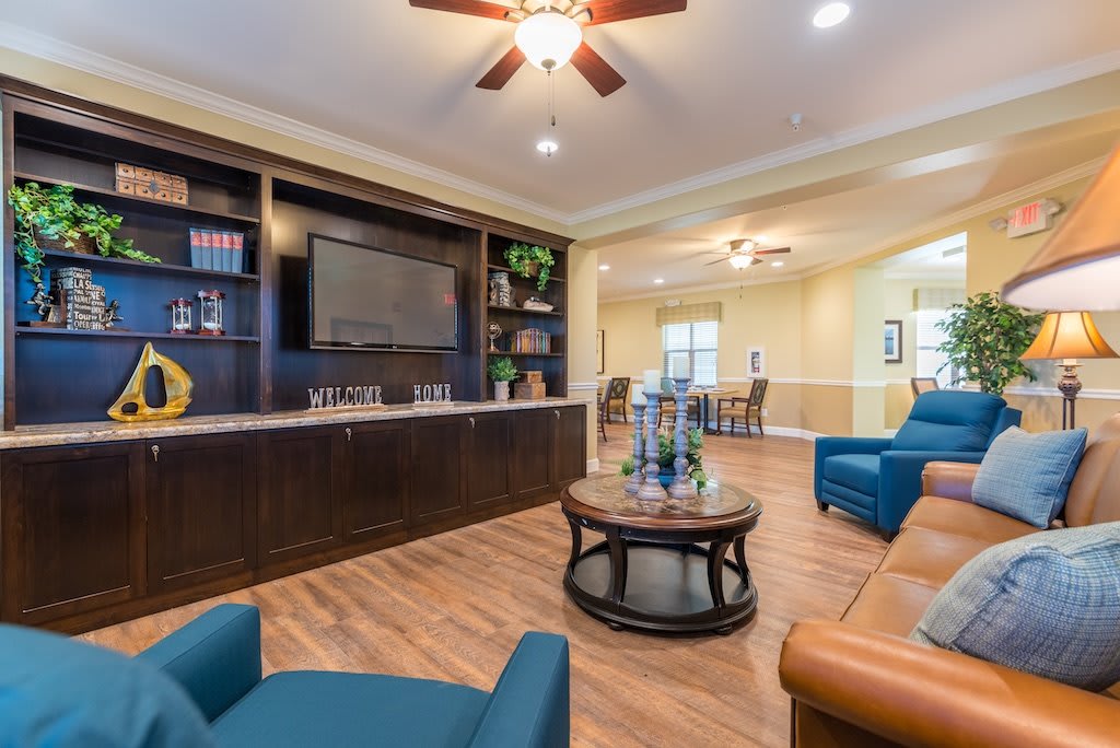 A cozy living room with a large television, bookshelves, and comfortable seating.