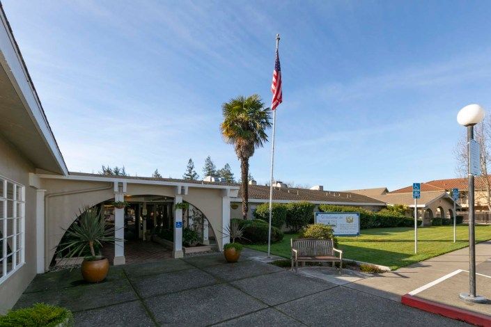 Entrance of a building with an American flag and palm tree in the foreground.