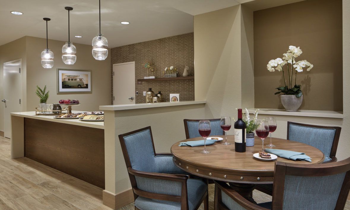 A cozy dining area with a round table set for dinner, featuring wine glasses and ambient lighting.