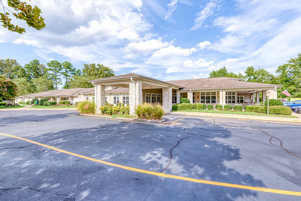 A commercial building with a parking lot under a partly cloudy sky.