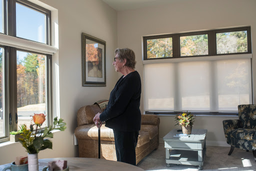 A woman stands by the window, enjoying the natural light in a cozy living space.