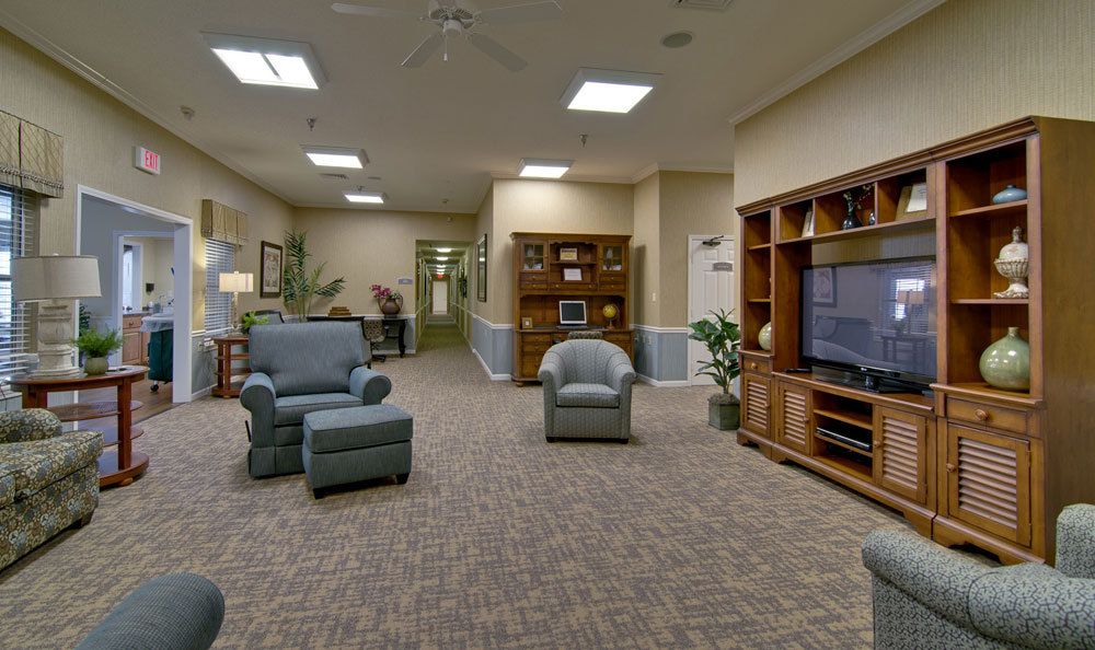 A cozy living room with armchairs, a large television, and bookshelves.