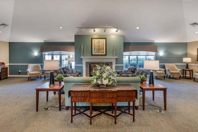 A cozy and elegantly furnished living room with sofas, tables, and decor, featuring a central fireplace.