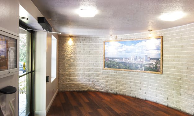 A modern room with a brick wall and wood flooring, featuring artwork and soft lighting.