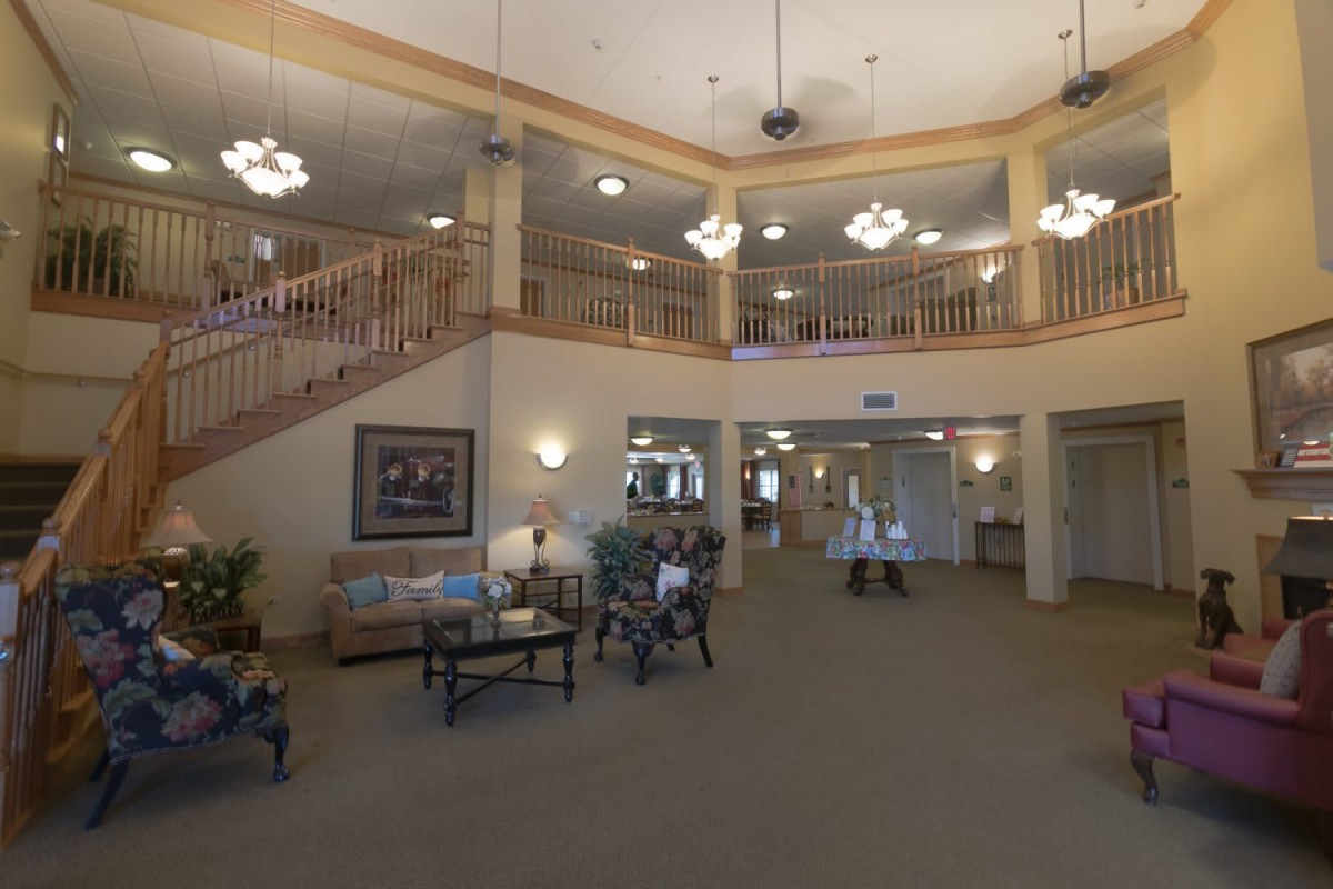 A spacious lobby with a staircase, seating area, and warm lighting.