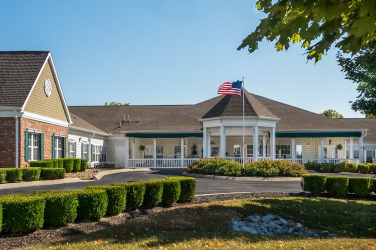 A well-maintained single-story building with an American flag flying, surrounded by manicured landscaping.