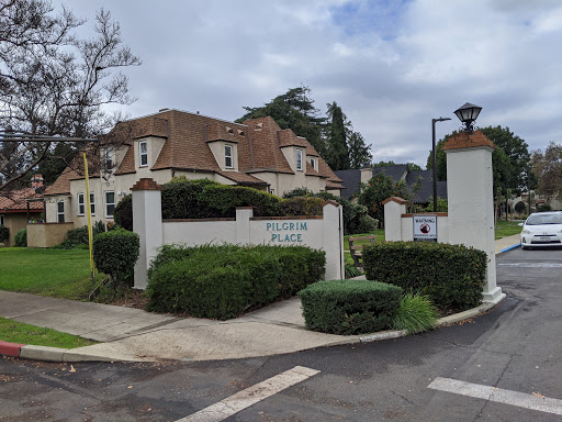 A charming residential entrance with well-maintained landscaping under a cloudy sky.