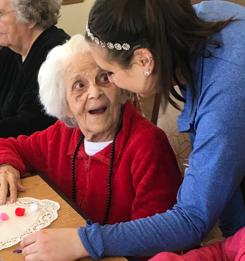 A joyful moment between a caregiver and an elderly woman during a community activity.