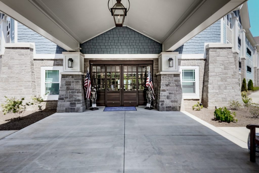 A covered entrance of a building with American flags flanking the doorway.