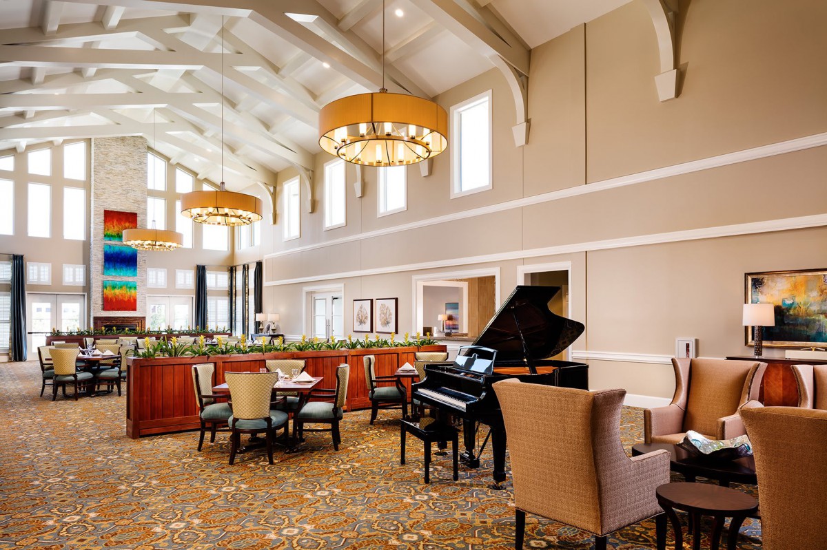 A spacious lounge with comfortable seating, featuring a grand piano and elegant chandeliers.