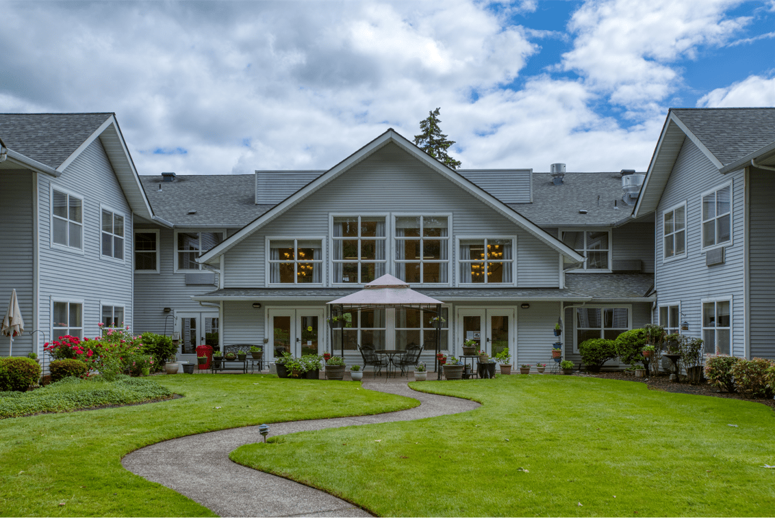A spacious two-story house with a well-maintained lawn and a cloudy sky backdrop.