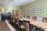 A well-lit conference room with a long table and chairs, featuring framed artwork on the wall.