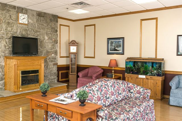 A cozy living room with a fireplace, floral sofa, and an aquarium.