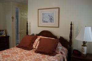 A cozy bedroom with a wooden bed and framed artwork above.