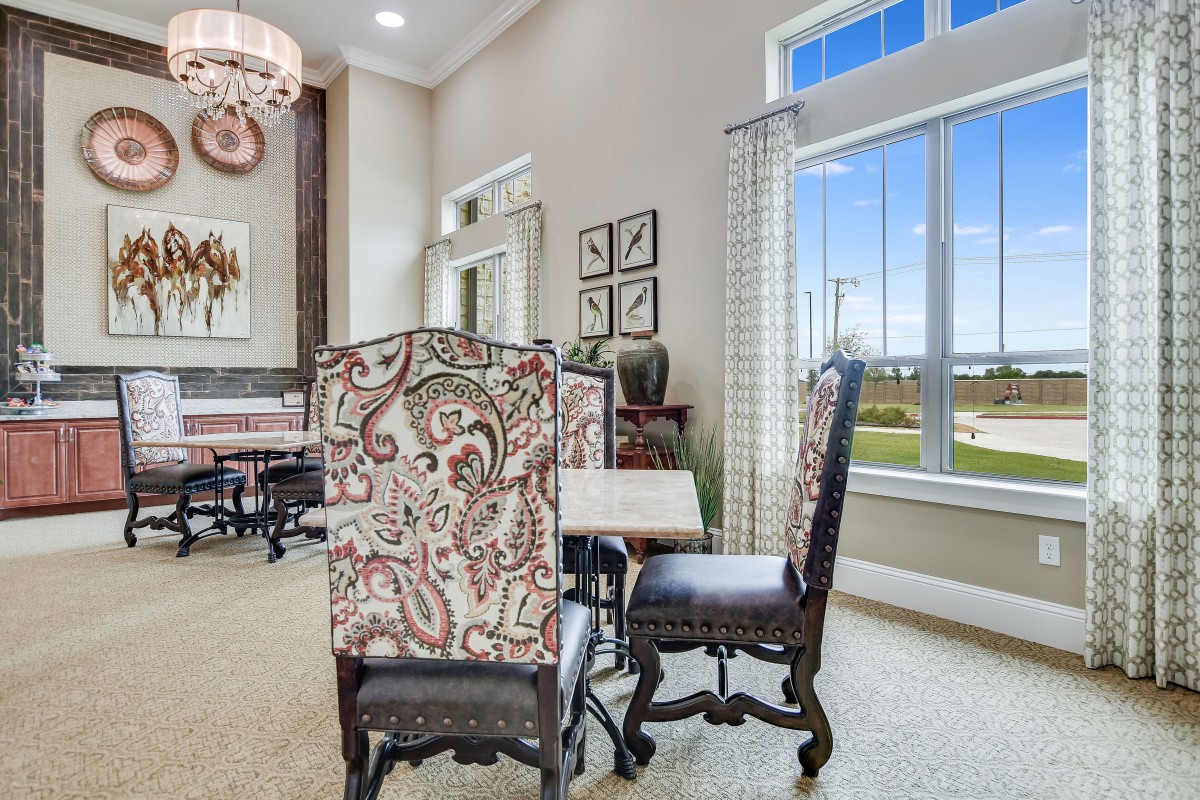 Elegant dining room with patterned chairs and a large window.
