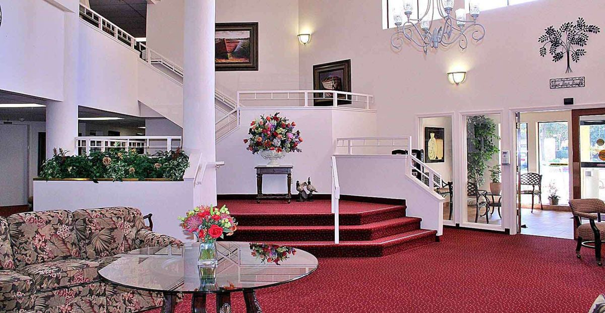 Elegant interior with a red-carpeted staircase and floral decorations.