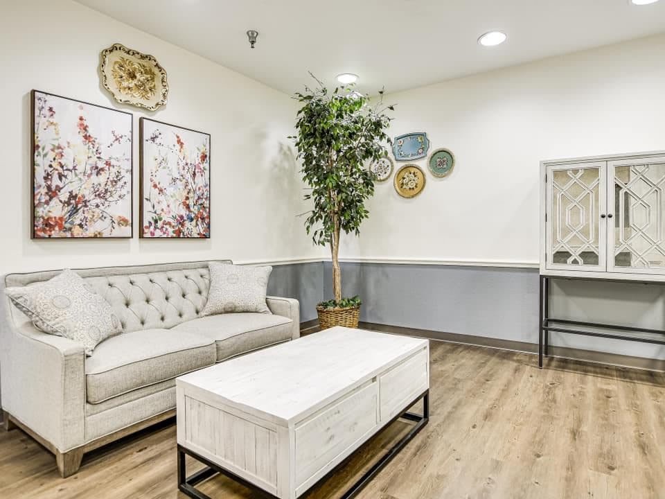 A cozy and elegantly decorated living room with a comfortable couch, modern coffee table, wall art, and lush green plant.