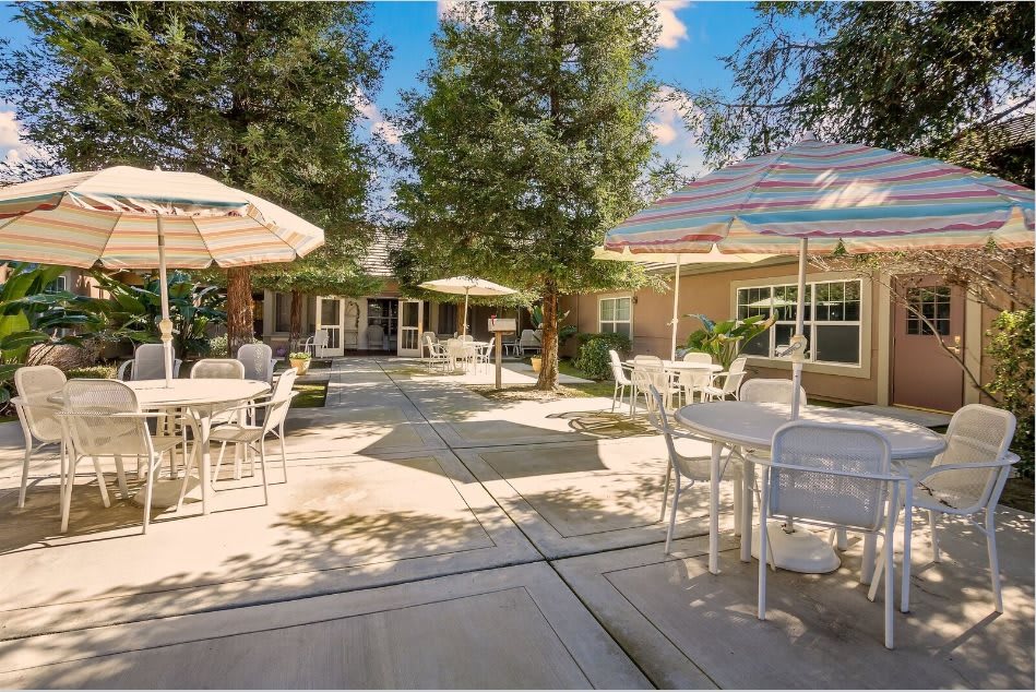 An inviting outdoor patio with tables and umbrellas under a clear blue sky.