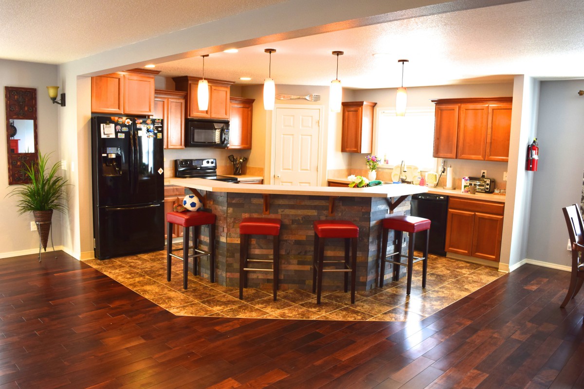 A modern kitchen with a central island, surrounded by bar stools and illuminated by pendant lights.