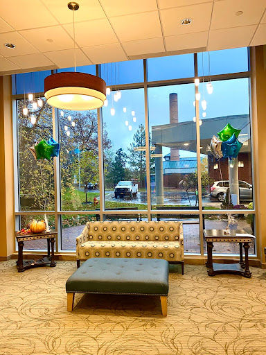 A stylish lobby featuring a comfortable seating area, large windows allowing natural light, and modern lighting fixtures.