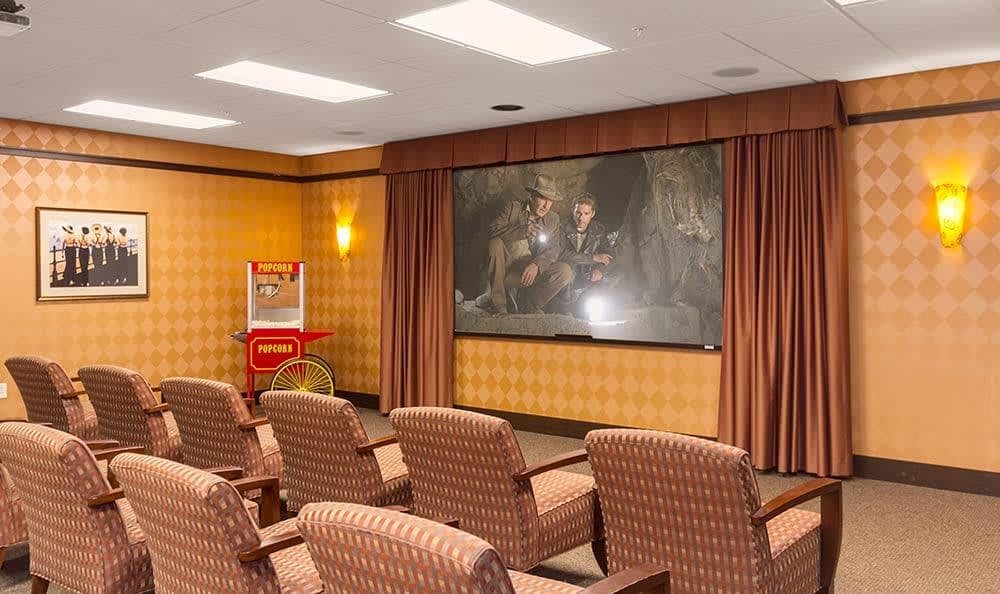 A cozy home theater setup with comfortable chairs and a large screen, complete with a classic popcorn machine in the corner.