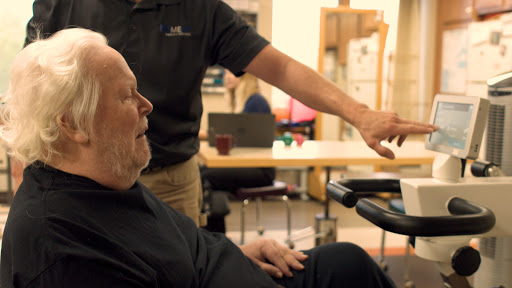 A caregiver assists an elderly man in using technology.