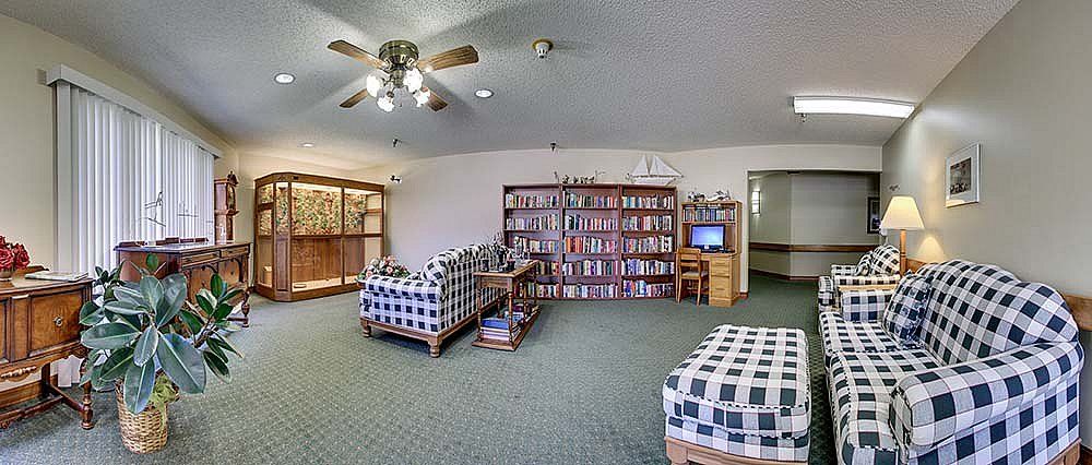 A cozy living room featuring a large bookshelf, checkered sofas, and a small television.