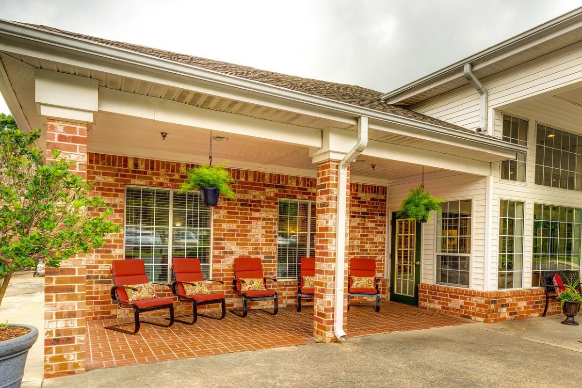 A cozy patio area with brick walls, furnished with comfortable seating and adorned with hanging plants.