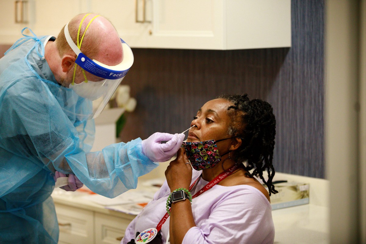 A healthcare worker wearing PPE administers a COVID-19 test to a patient.