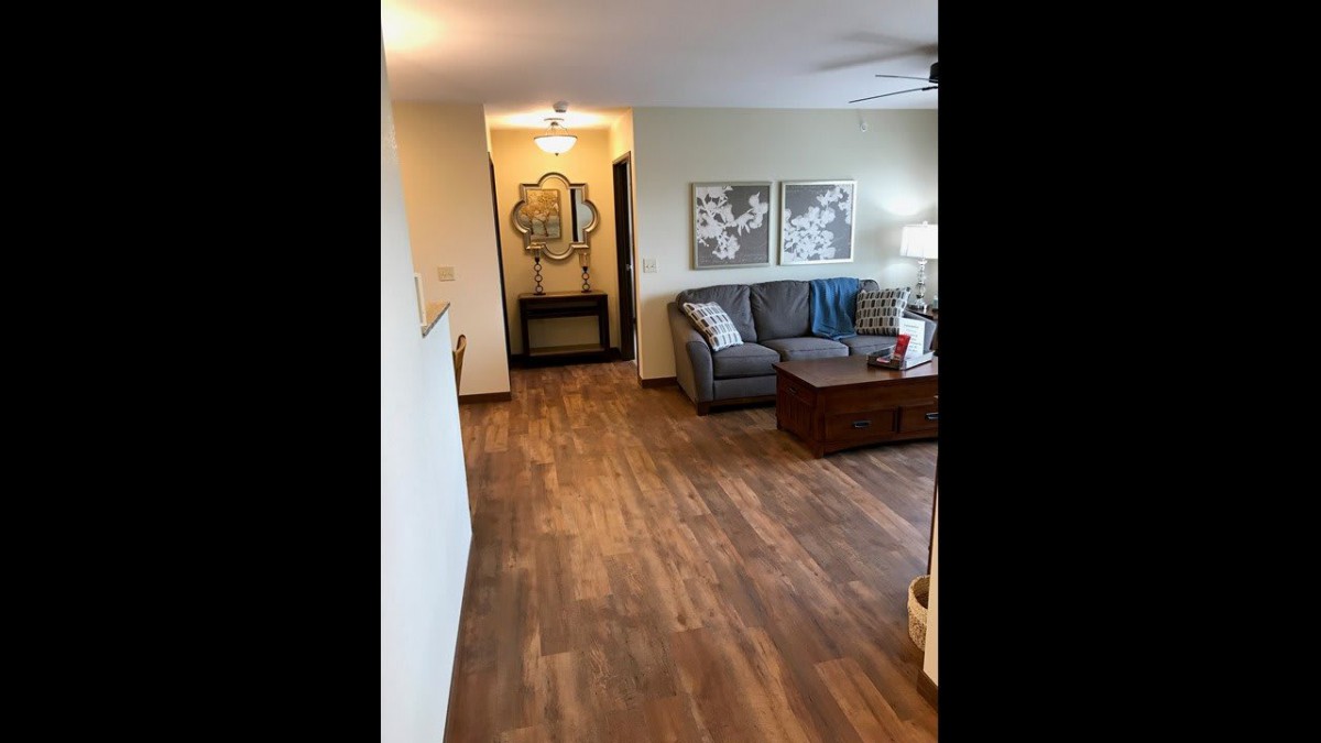 A cozy living room with a couch, coffee table, and wall artwork on wooden flooring.