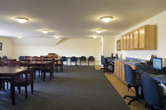 A spacious meeting room with tables and chairs arranged on a carpeted floor.